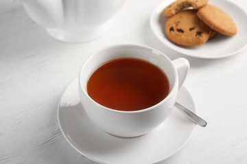 Cup of delicious tea with saucer on table