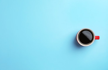 Ceramic cup with hot aromatic coffee on color background, top view