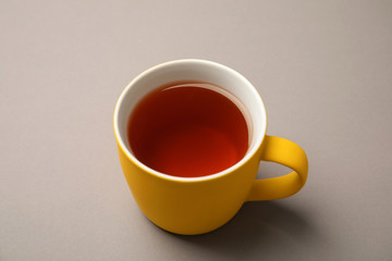 Cup of black tea on color background