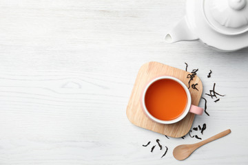 Cup of black tea on wooden table, top view