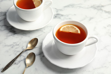 Cups with black tea and lemon on marble table