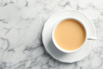 Cup with black tea and milk on marble table, top view
