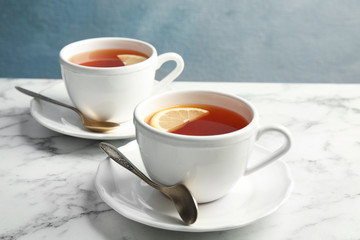 Cups with black tea and lemon on marble table