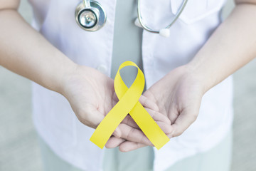 Yellow ribbon symbolic color for Sarcoma Bone cancer, Spina Bifida Awareness Month and suicide prevention on doctor’s hand
