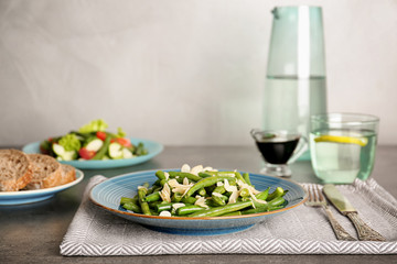Plate with tasty green beans and almonds on table