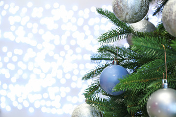 Fototapeta na wymiar Christmas tree with festive decor against blurred fairy lights