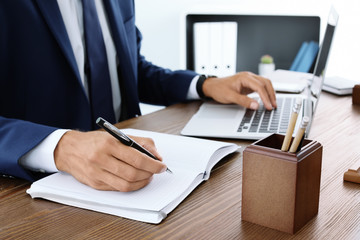 Lawyer working with laptop and notebook at table, closeup
