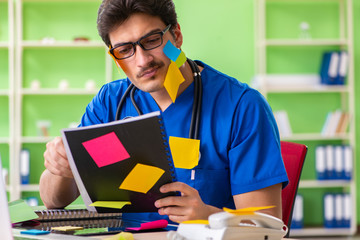 Young doctor sitting in hospital with many conflicting prioritie