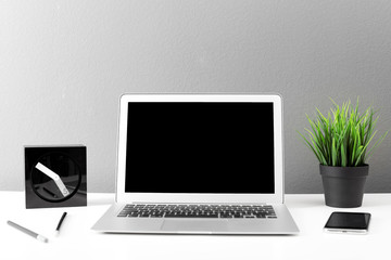 Fototapeta premium Modern laptop on table against gray wall. Mock up with space for text