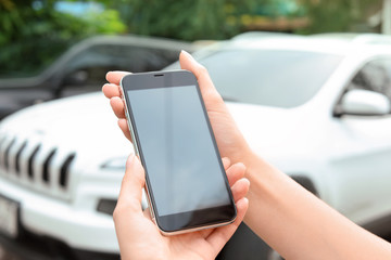 Woman holding modern smartphone outdoors. Mock up with space for text