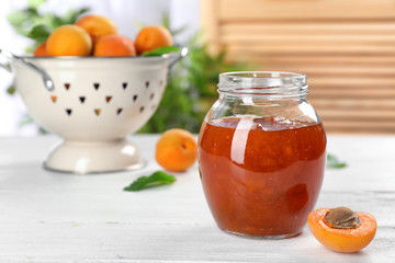 Jar with tasty apricot jam on table