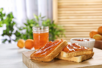 Bread with tasty apricot jam on wooden board