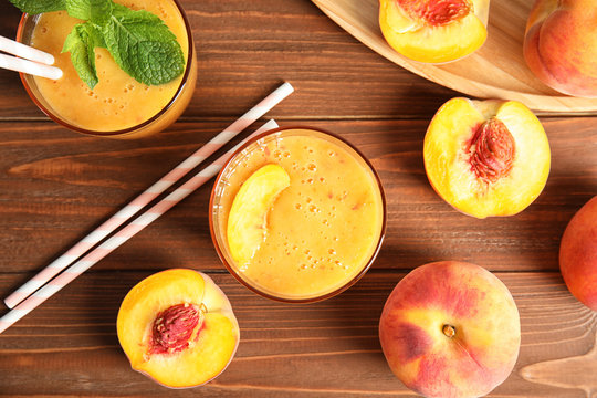 Tasty peach smoothie and fresh fruit on wooden background, top view