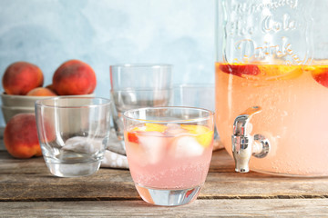 Peach cocktail in glass and jar with tap on table. Refreshing drink