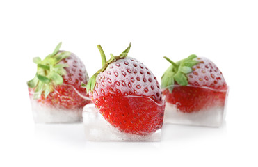 Fresh strawberries frozen in ice cubes on white background