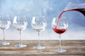 Pouring delicious red wine into glass on table