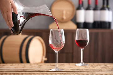 Pouring delicious red wine into glass on table