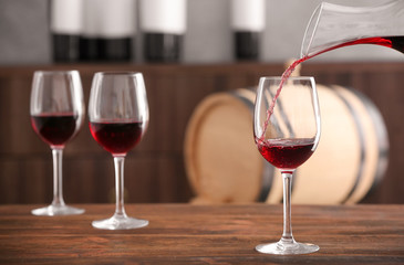 Pouring delicious red wine into glass on table