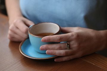 Woman with cup of fresh aromatic coffee at table, closeup