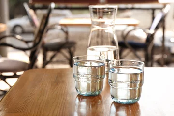 Fotobehang Water Glaswerk met water op houten tafel binnenshuis