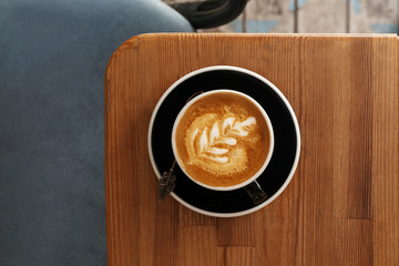 Cup of fresh aromatic coffee on wooden table, top view