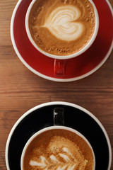 Cups of fresh aromatic coffee on wooden table, top view