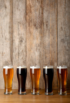Glasses with beer on table against wooden background