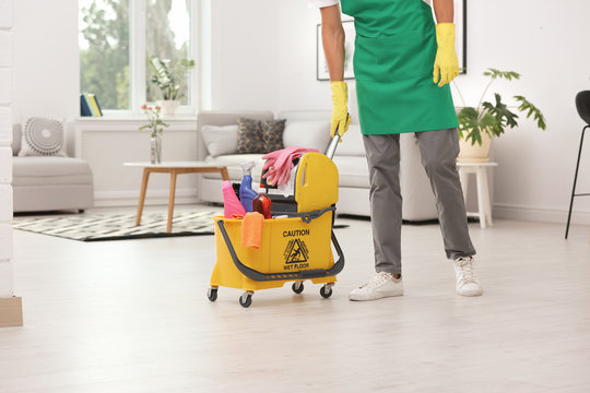 Man in uniform with cleaning supplies indoors