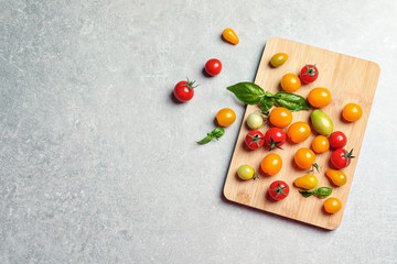 Wooden board with juicy tomatoes and space for text on grey background, top view