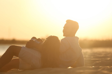 Happy young couple resting together on beach at sunset
