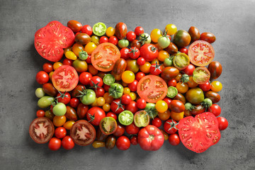 Flat lay composition with different tomatoes on gray background