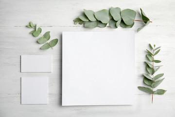 Fresh eucalyptus leaves and blank cards with space for design on wooden background, top view © New Africa