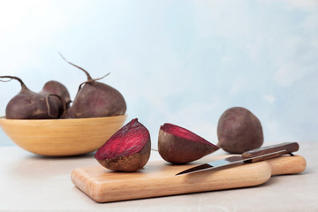 Wooden board with ripe beets on table