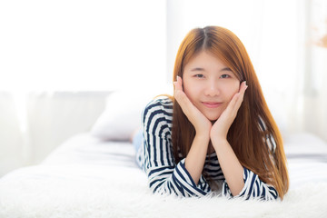 Beautiful portrait young asian woman lying and smile while wake up with sunrise at morning, lifestyle and relax concept.