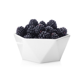 Bowl with ripe blackberries on white background