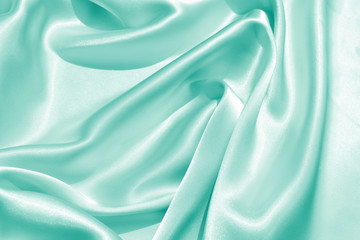 The texture of the satin fabric of green color for the background 