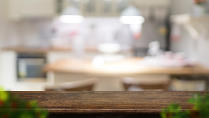 Empty dark brown wooden table top with blurred home kitchen with blur foreground leaf,Mock up template for display or montage of your design,Banner for advertise of product,panorama view.
