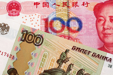 A close up image of a 100 Chinese yuan bank note with a 100 Russian ruble bank note 