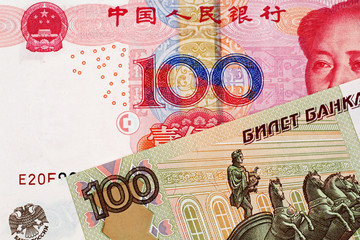 A close up image of a 100 Chinese yuan bank note with a 100 Russian ruble bank note 