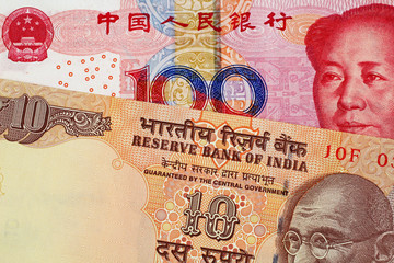 A close up image of a 100 Chinese yuan bank note with a 10 Indian Rupee bank note 