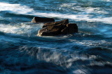 Fototapeta premium Blurred ocean waves and rocks, background, abstract 