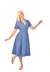 Fototapeta premium full length portrait of blonde girl wearing blue dress, standing pose. isolated on white studio background.