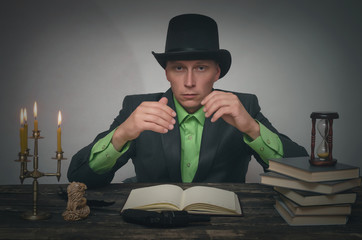 Confused man in bowler hat and suit is sitting by table. Writer, author, detective or spy agent...