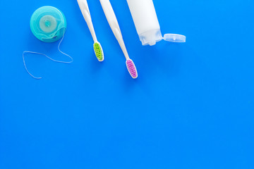 Set for daily teeth care. Toothbrush, tooth paste, dental floss on blue background top view copy...