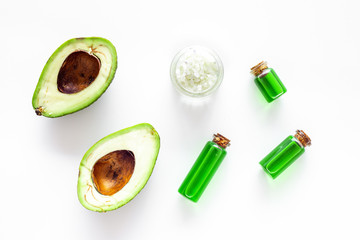 Cosmetics for skin care. Avocado oil near half of avocado on white background top view