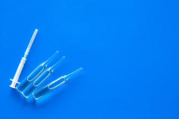 Flu vaccination concept. Syringe and ampoulie on blue background top view copy space