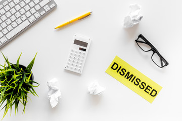 Dismissial concept. Sign Dismissed on office desk with computer keyboard and crumpled paper on white background top view
