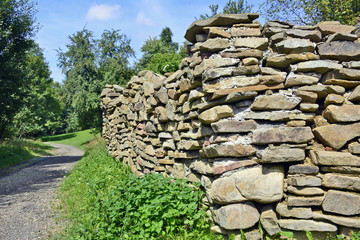 
Forest path with old stone wall built with natural wall stones of irregular shapes and sizes