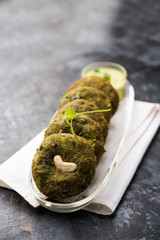 Hara bhara Kabab or Kebab is Indian vegetarian snack recipe served with green mint chutney over moody background. selective focus