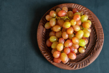 grape on brown plate on dark background with copy space